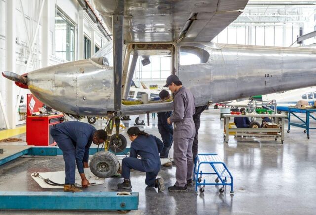 Three mechanics working on an airplane indoors