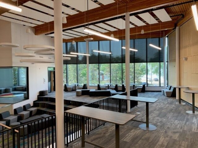A floor filled with many coffee tables and chairs with daylight